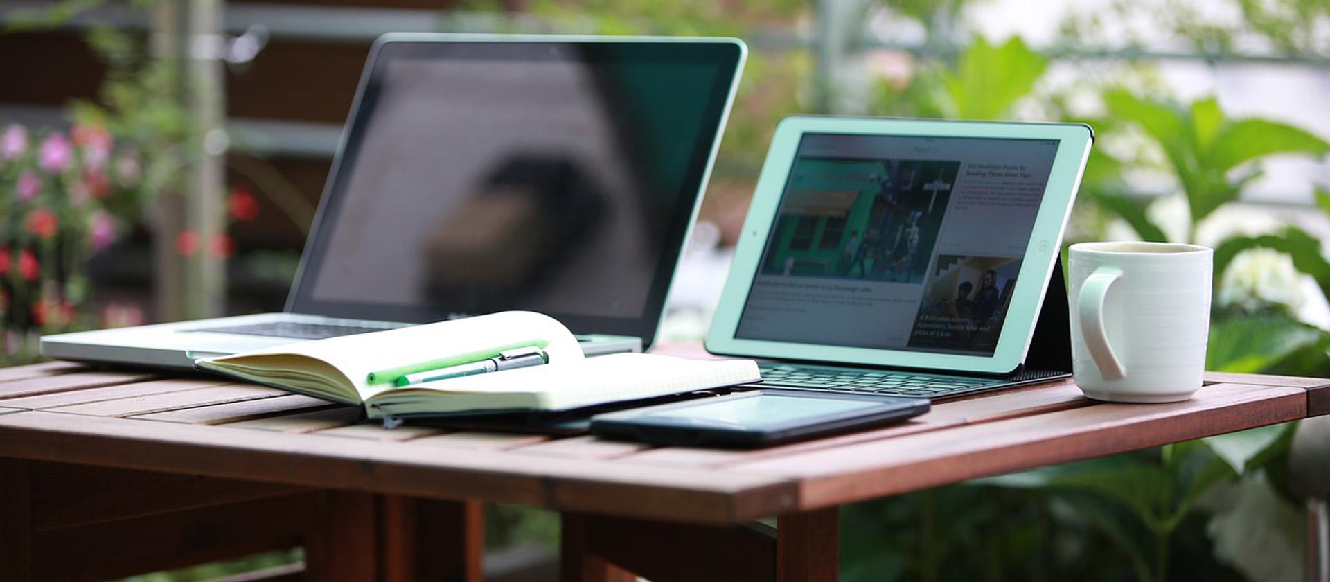 A computer, a tablet, a smartphone and a notebook on a table